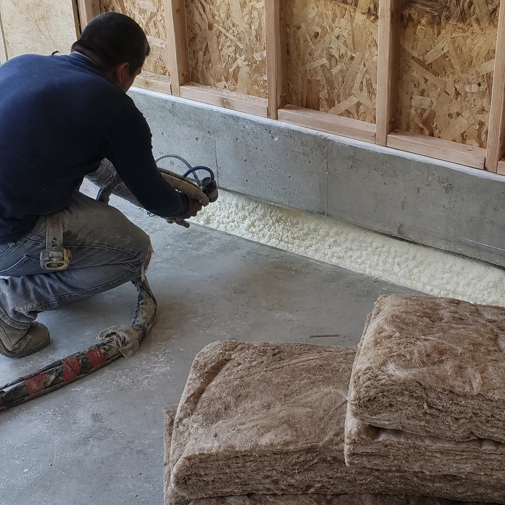 Contractor applying spray foam insulation for professional garage conversion project